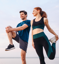Man and woman in sporty wear smiling and chatting while stretching before an outdoor exercise session